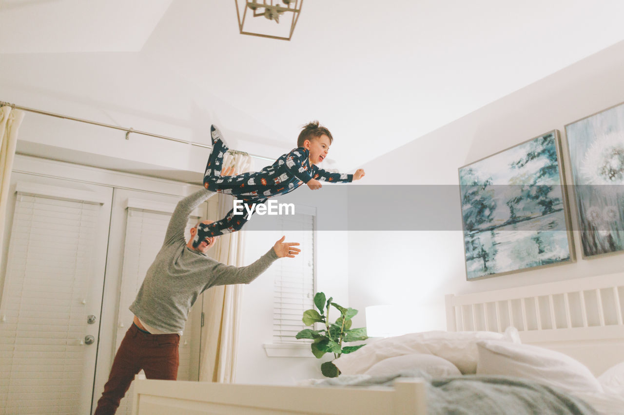 Father throwing son on bed at home