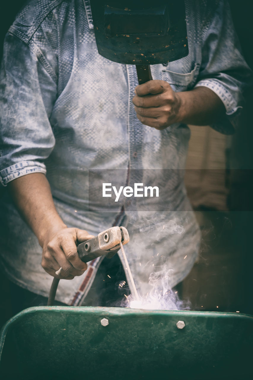 MIDSECTION OF MAN WORKING ON METAL