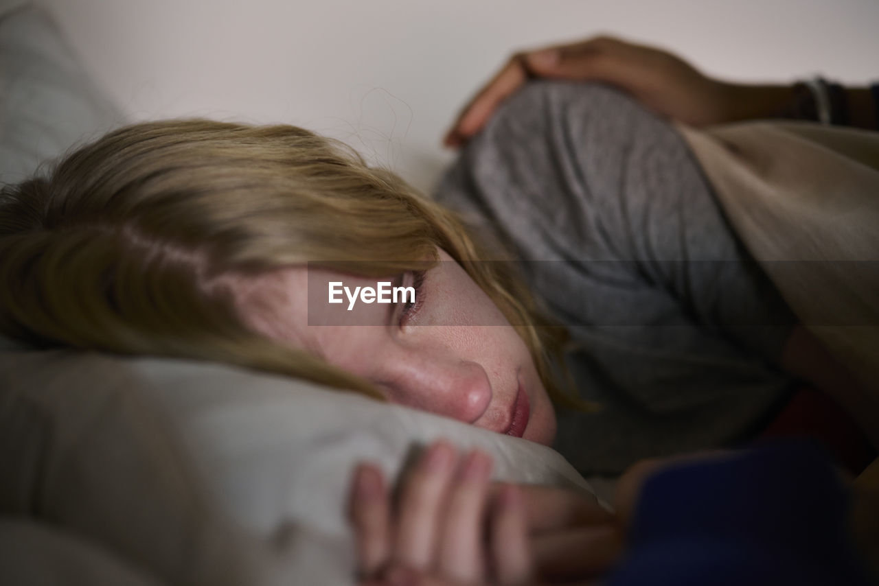 Crying young woman lying in bed