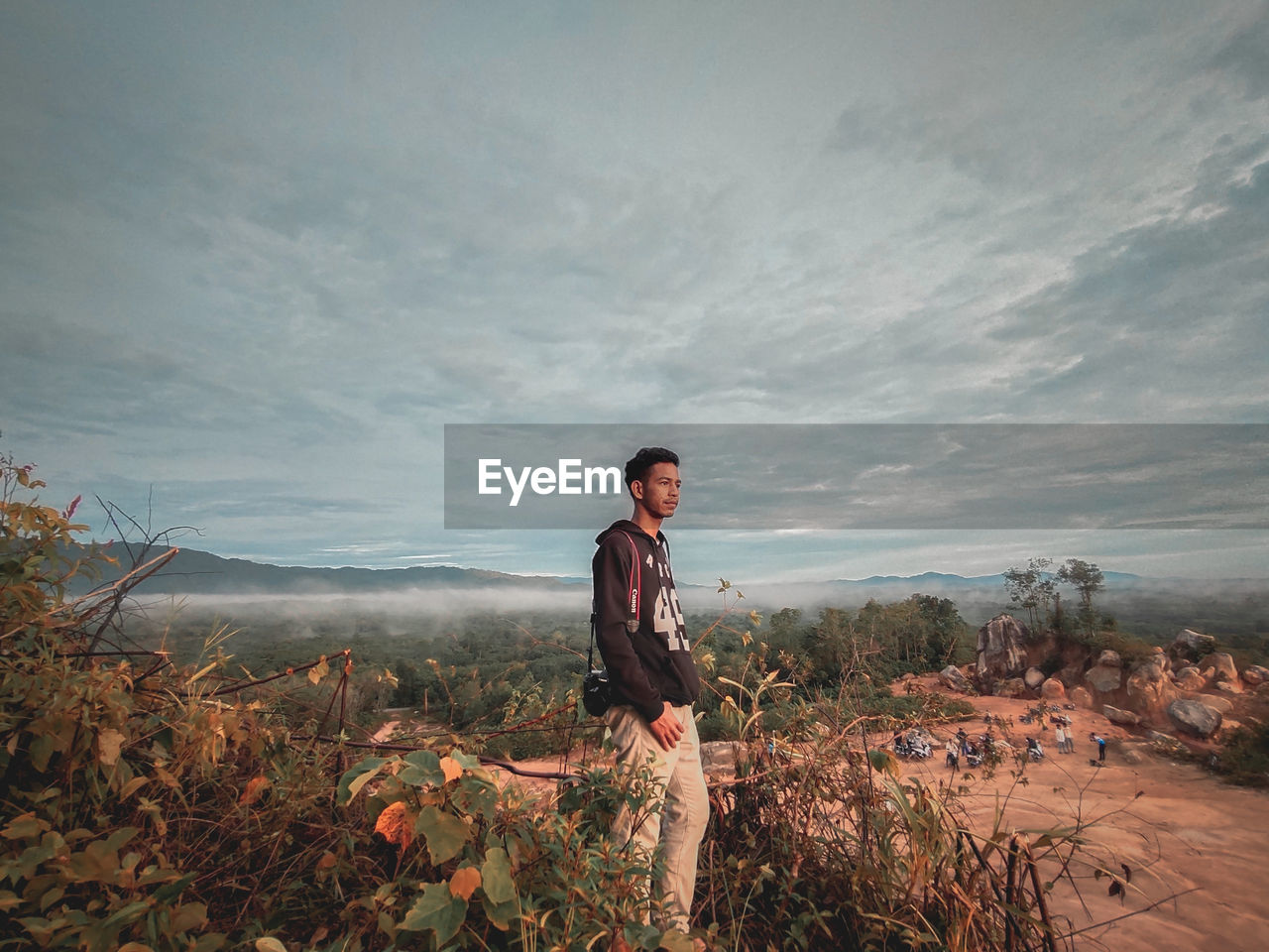 Side view of young man standing on land against sky