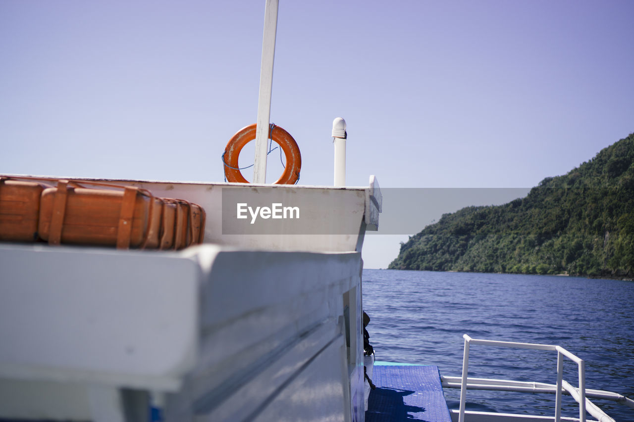 CLOSE-UP OF BOAT SAILING ON SEA AGAINST CLEAR SKY