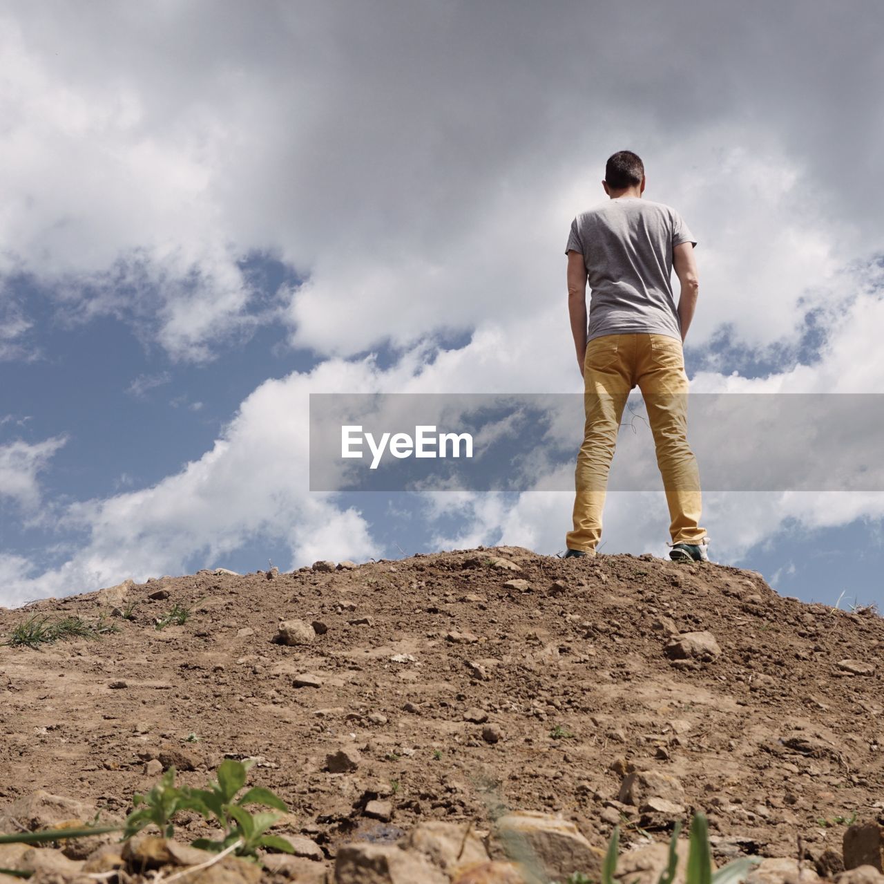 Rear view of man standing on mountain against sky