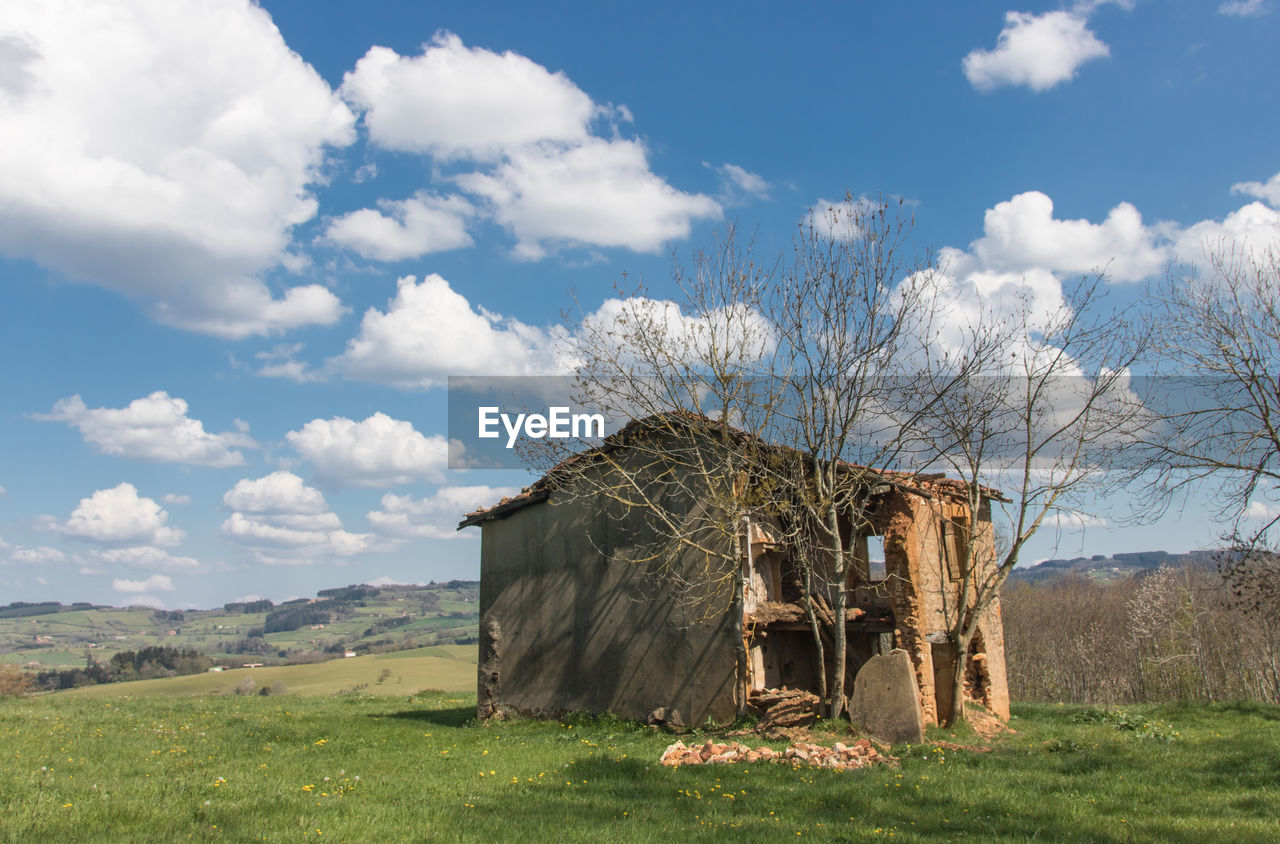 Abandoned house on field against sky