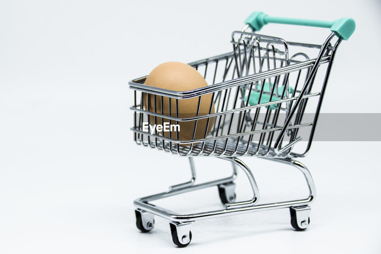 Close-up of egg in shopping cart on white background