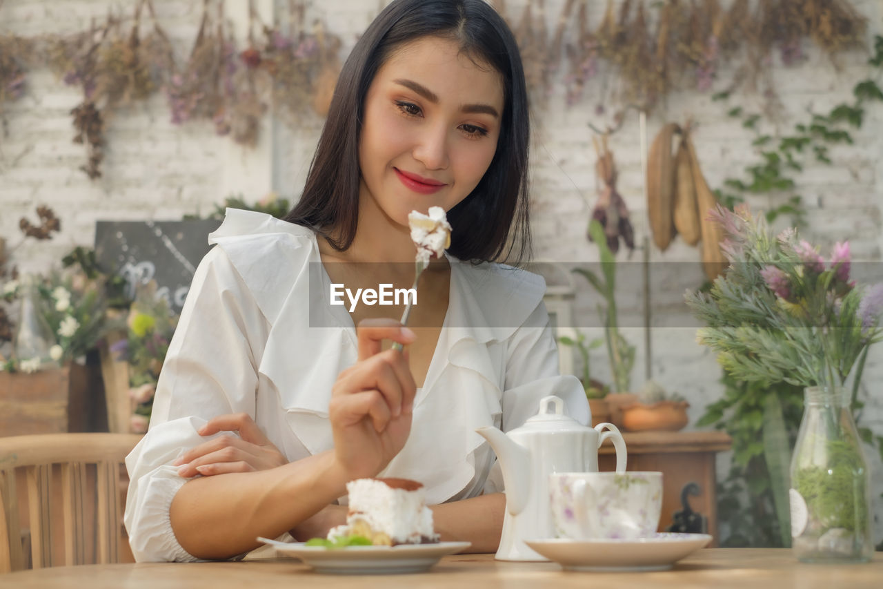 Beautiful woman sits eating cake and tea at vintage cafe