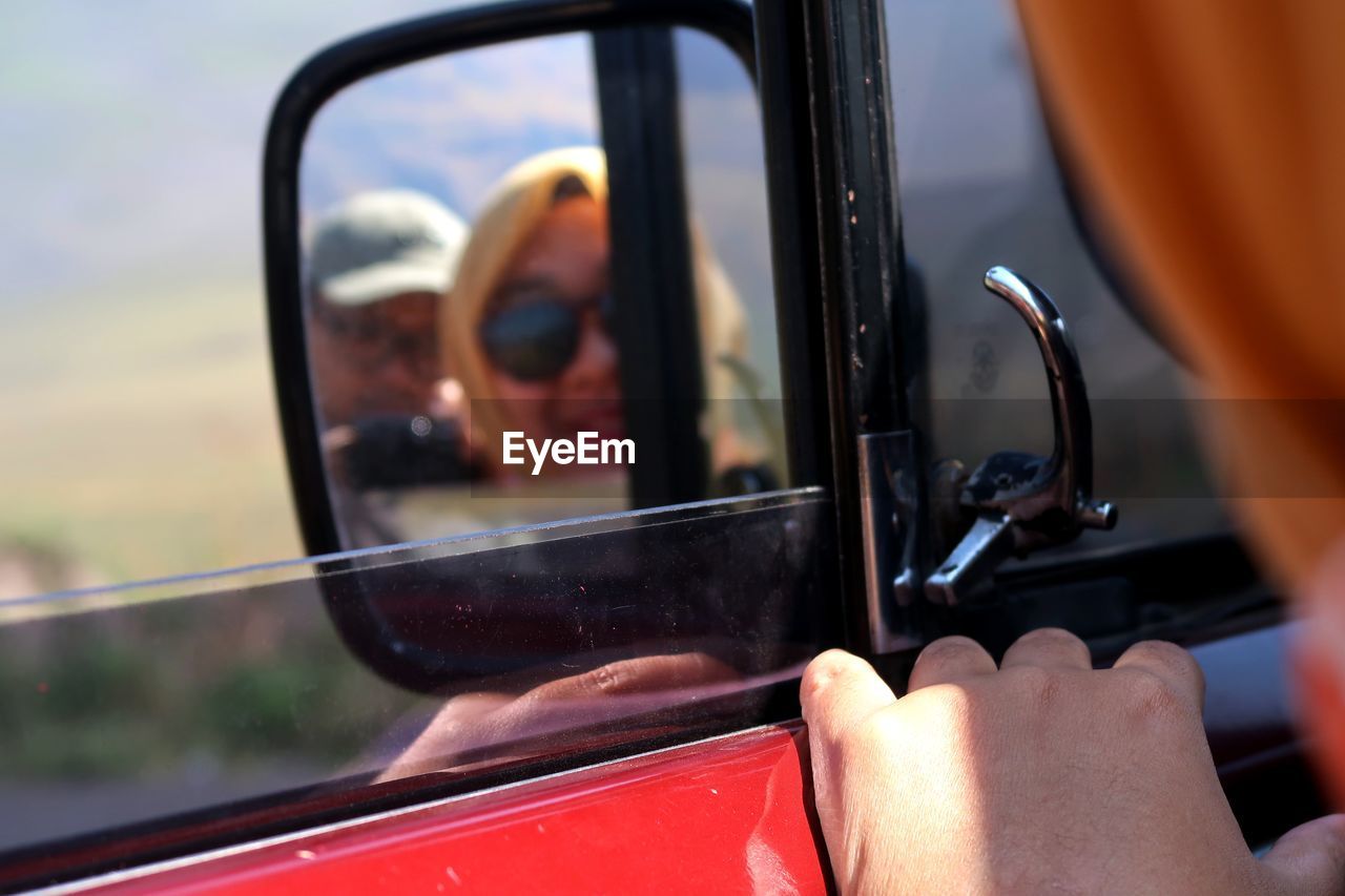 Reflection of man and woman on side-view mirror