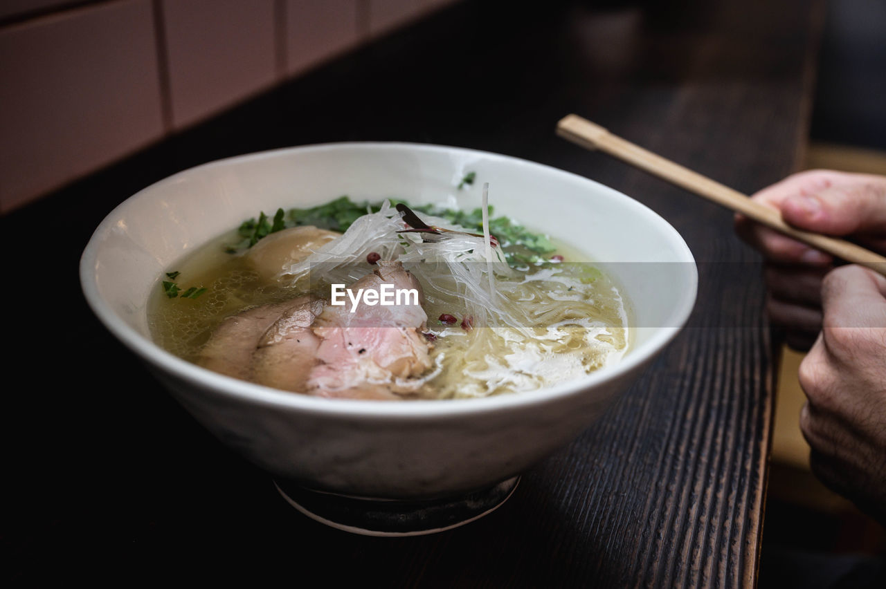  a bowl shio ramen, man holding chopsticks and ready to start the dinner, winter comfort food