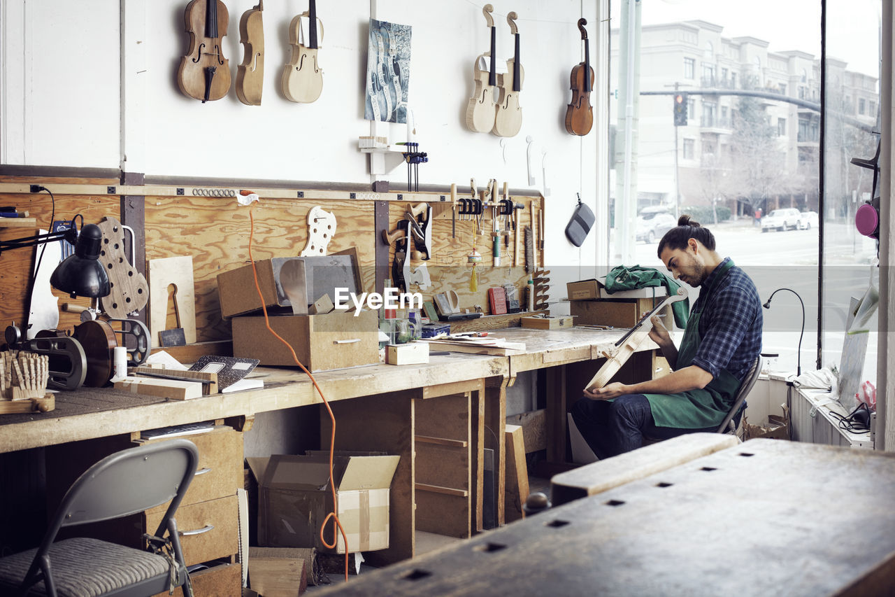 Man making violin while working in workshop