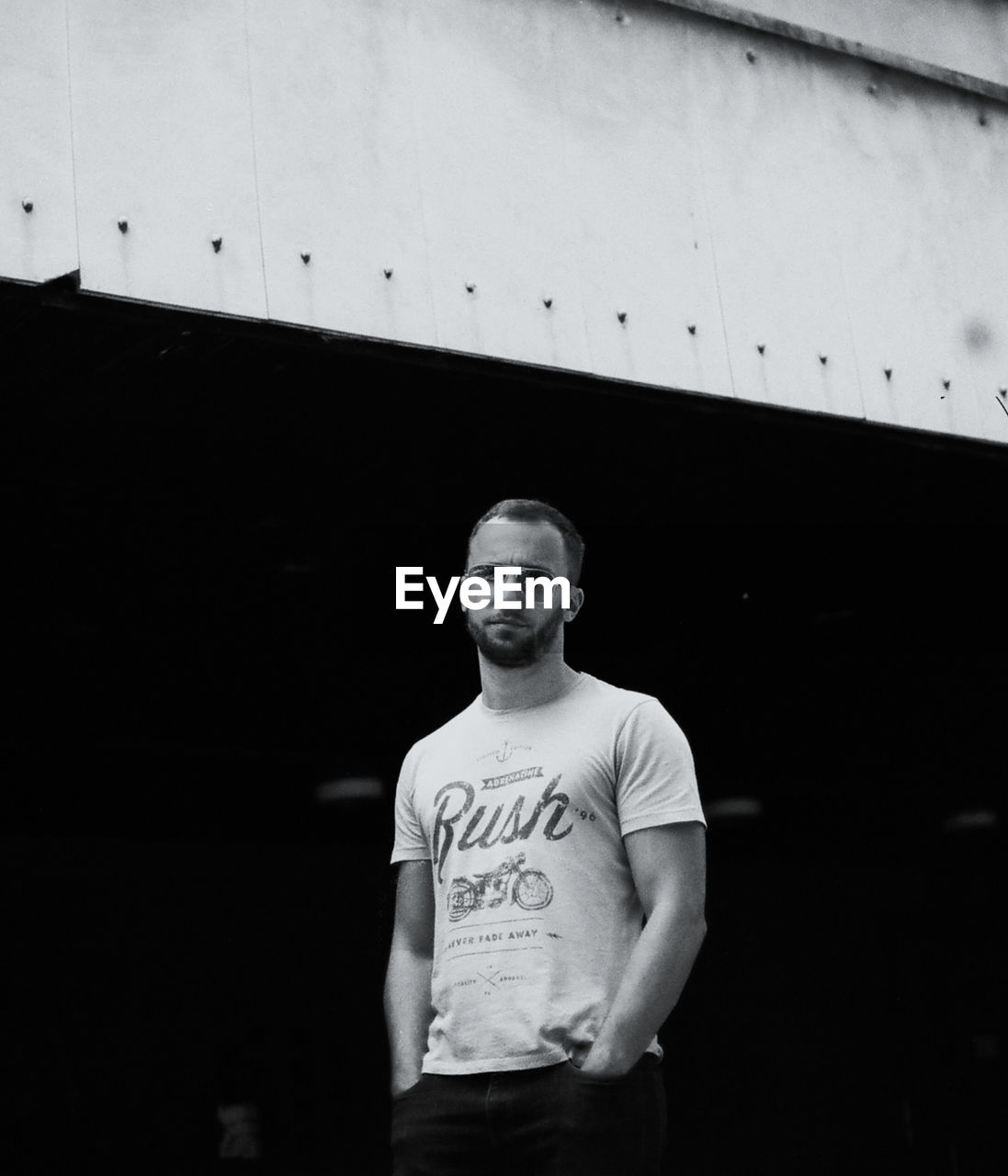 PORTRAIT OF YOUNG MAN STANDING AGAINST CURTAIN