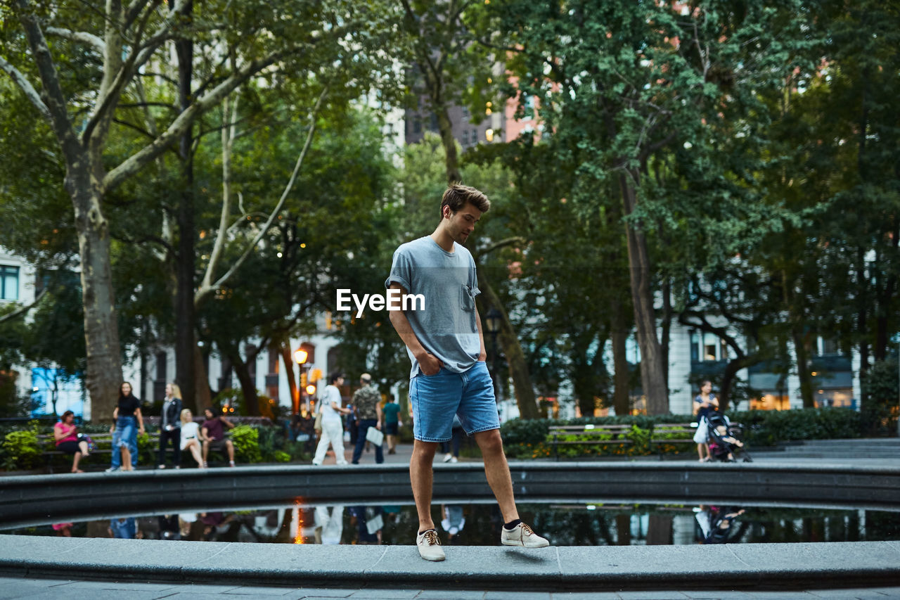 Young man standing by fountain at park