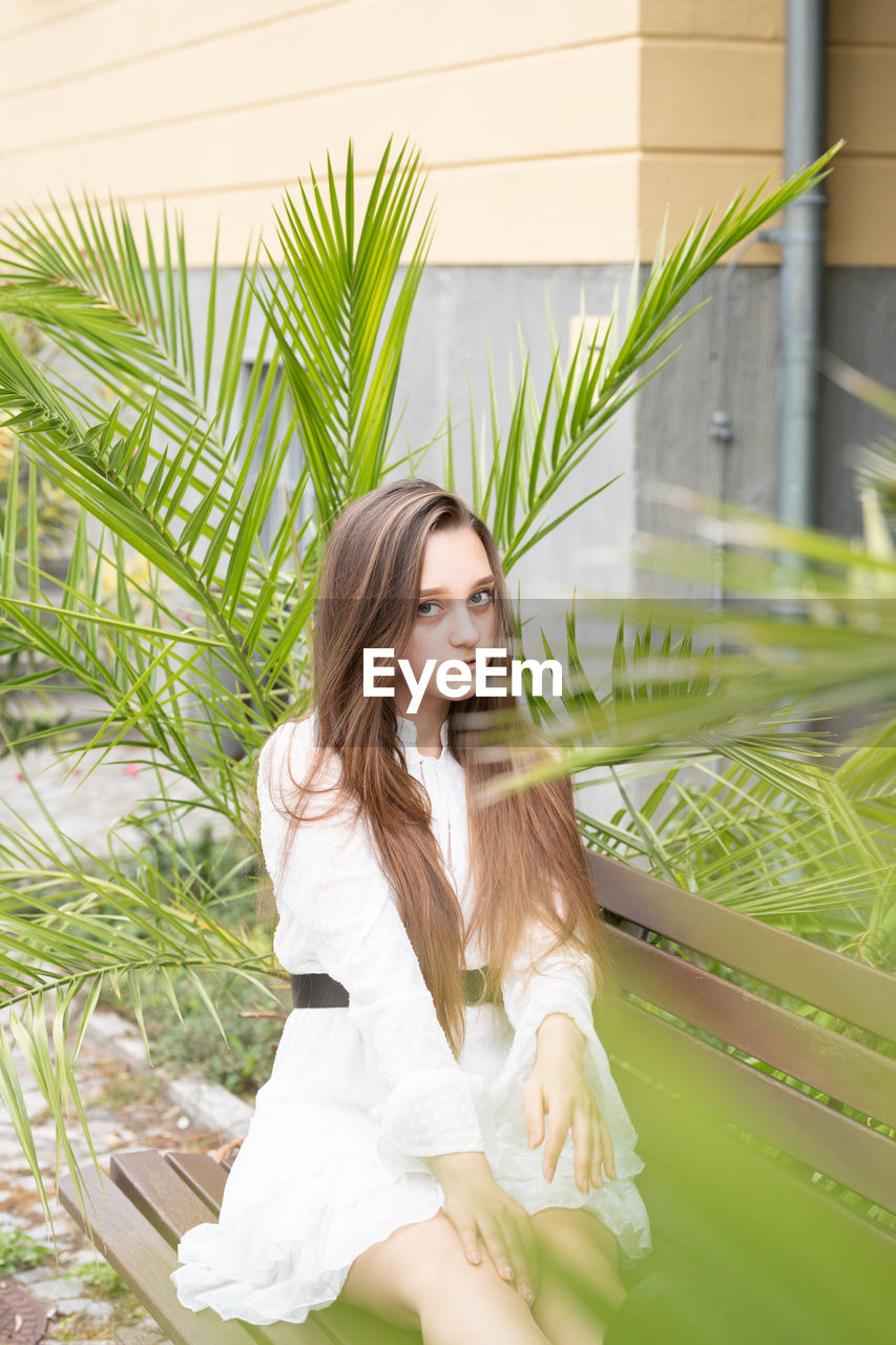 Young woman looking away while sitting outdoors