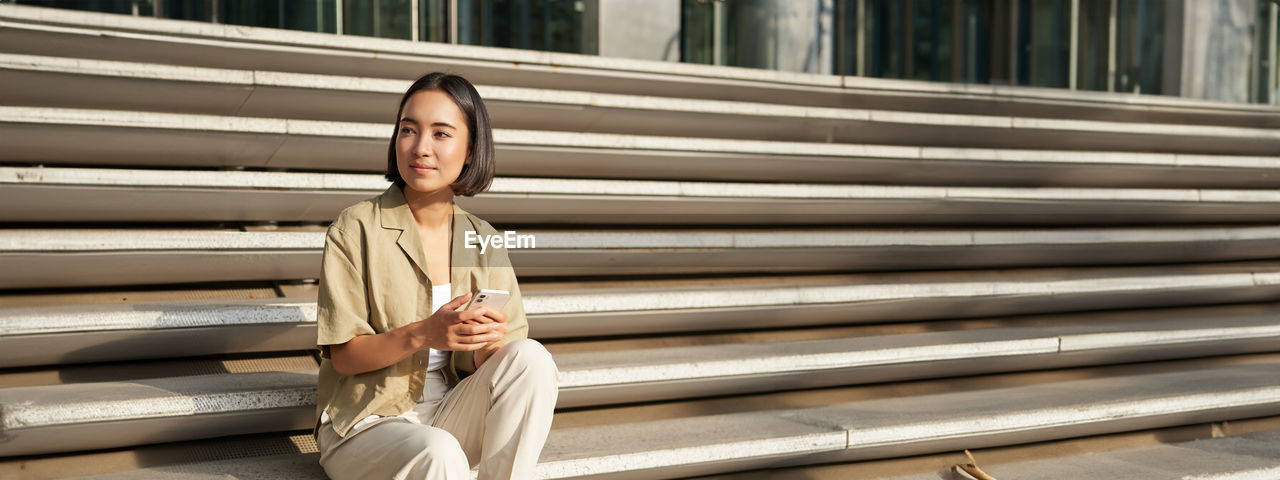 full length of woman standing against wooden wall