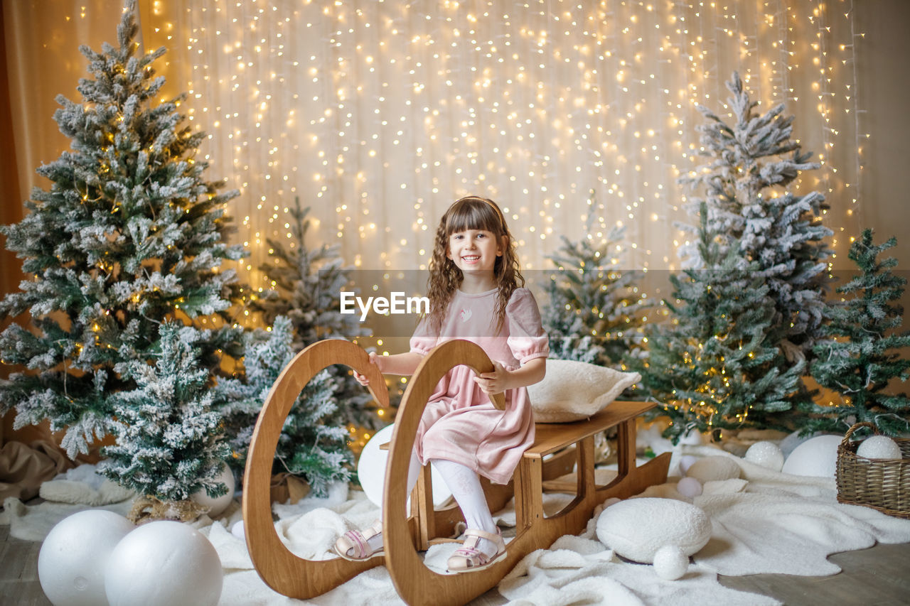 portrait of woman sitting by christmas tree