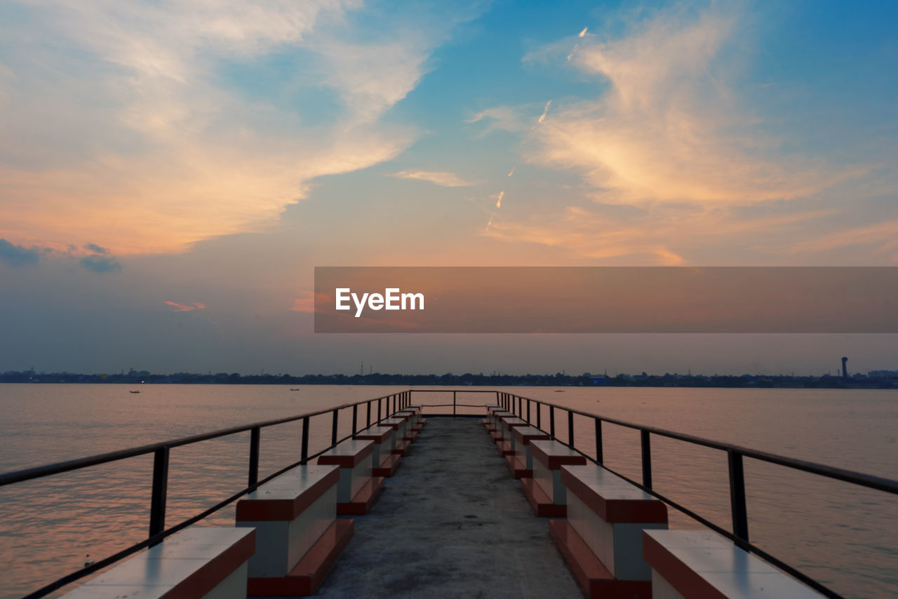 Pier over sea against sky during sunset