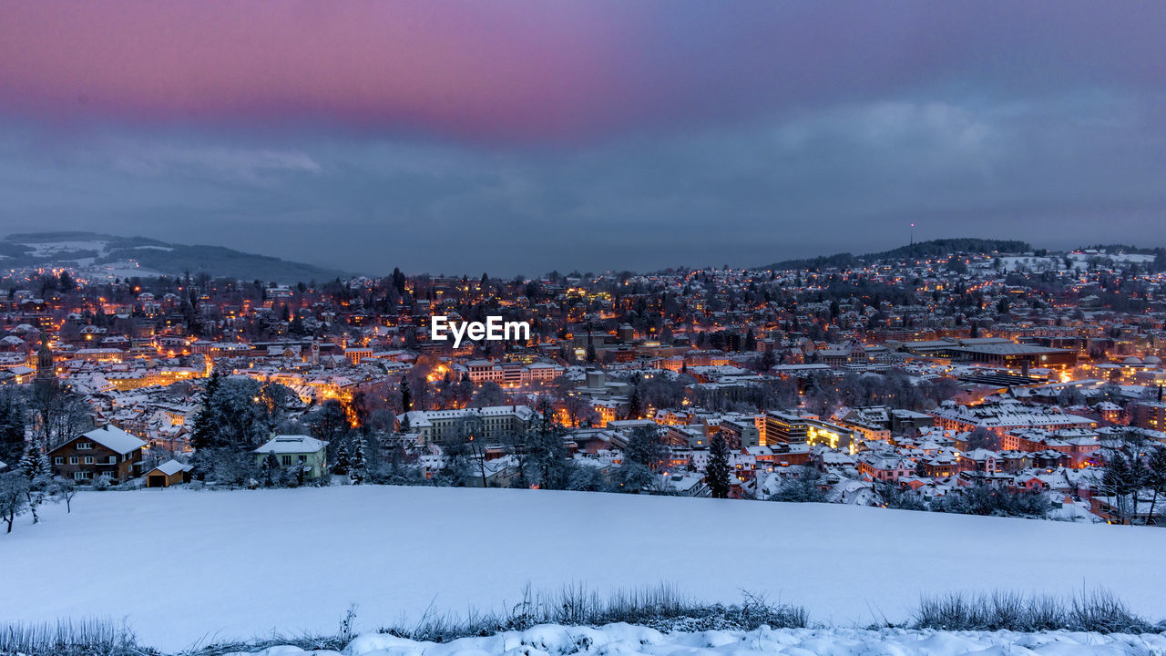 Illuminated city against sky during winter