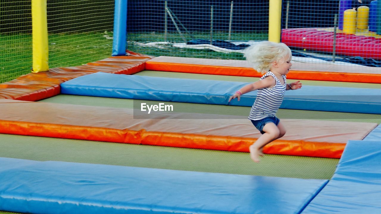 Side view of girl jumping at bouncing castle