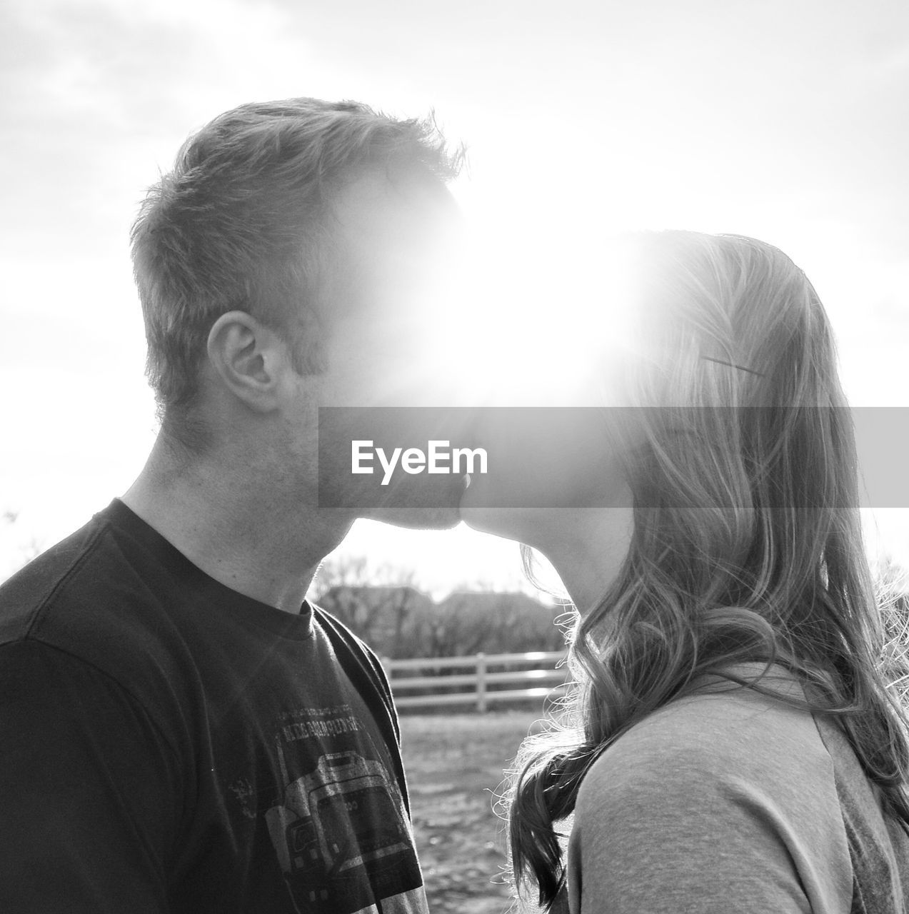 Couple kissing against bright sky