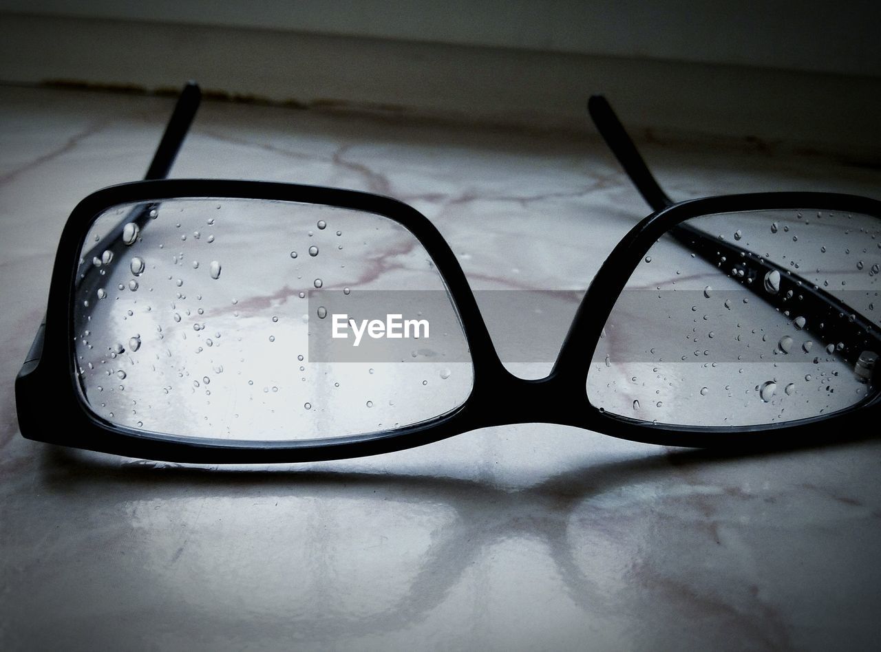 Close-up of wet eyeglasses on tiled floor at home