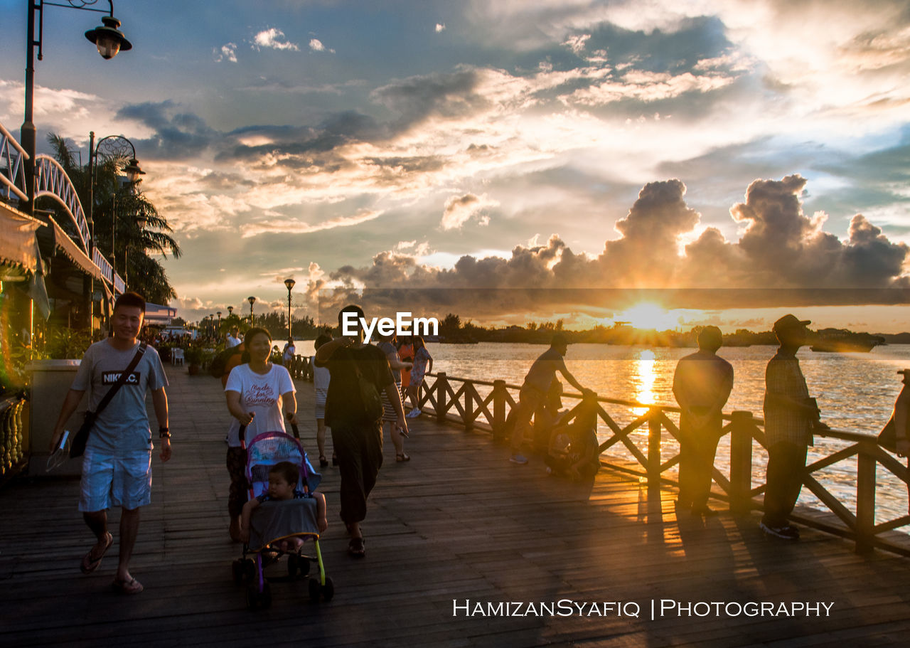 PANORAMIC SHOT OF PEOPLE AT BEACH DURING SUNSET