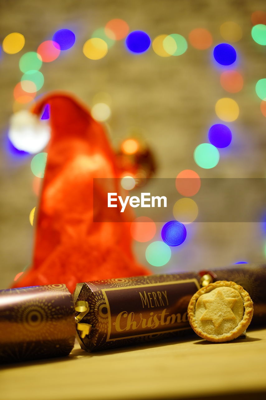 Close-up of cookie and gifts on table against defocused lights at night