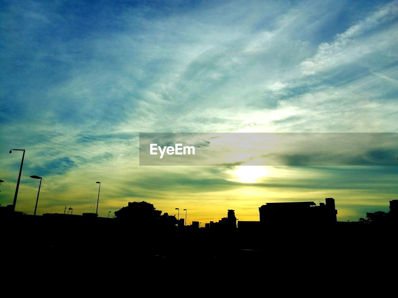 Silhouette built structures against sky at sunset