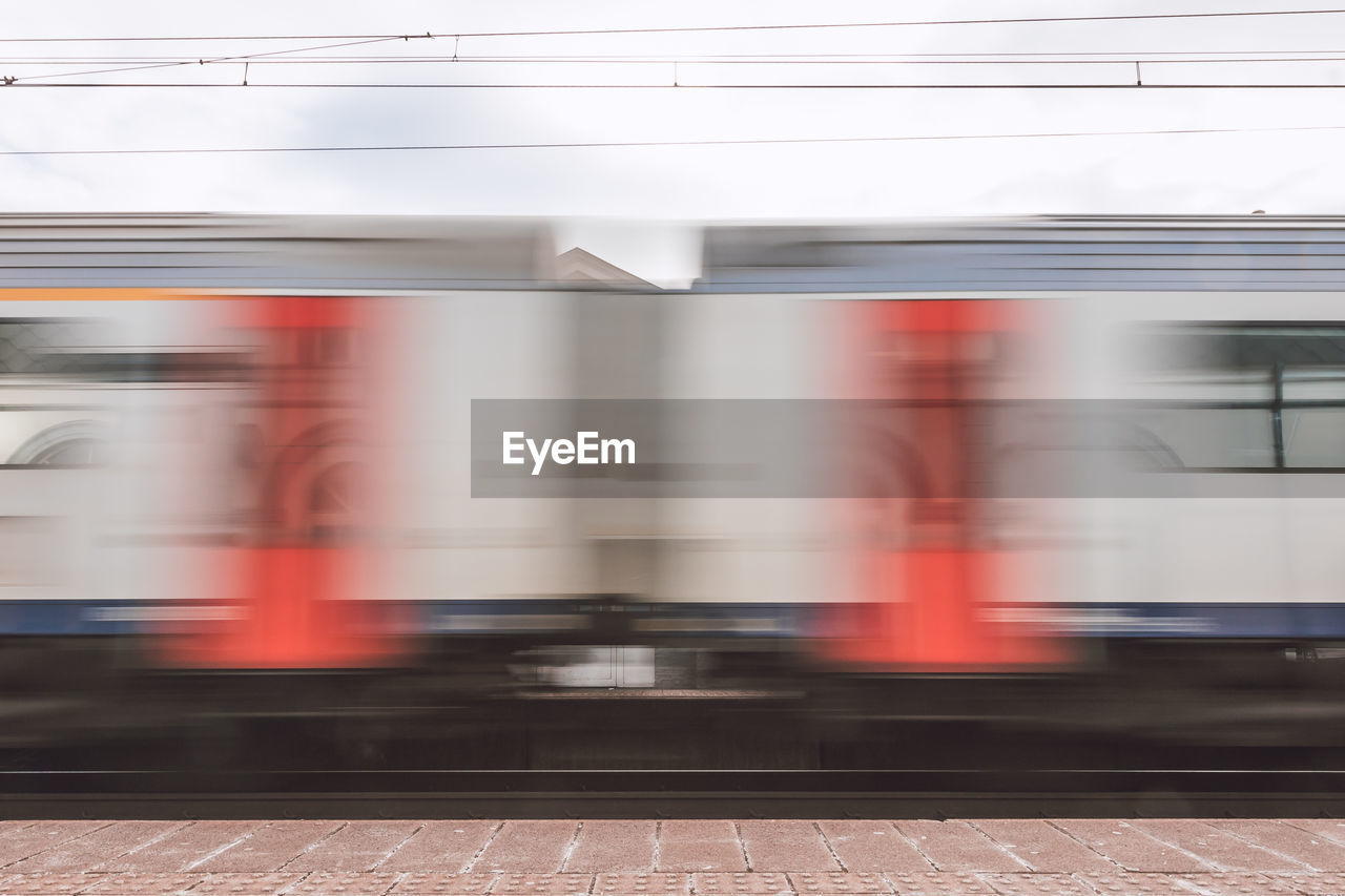 BLURRED MOTION OF TRAIN ON RAILROAD STATION PLATFORM