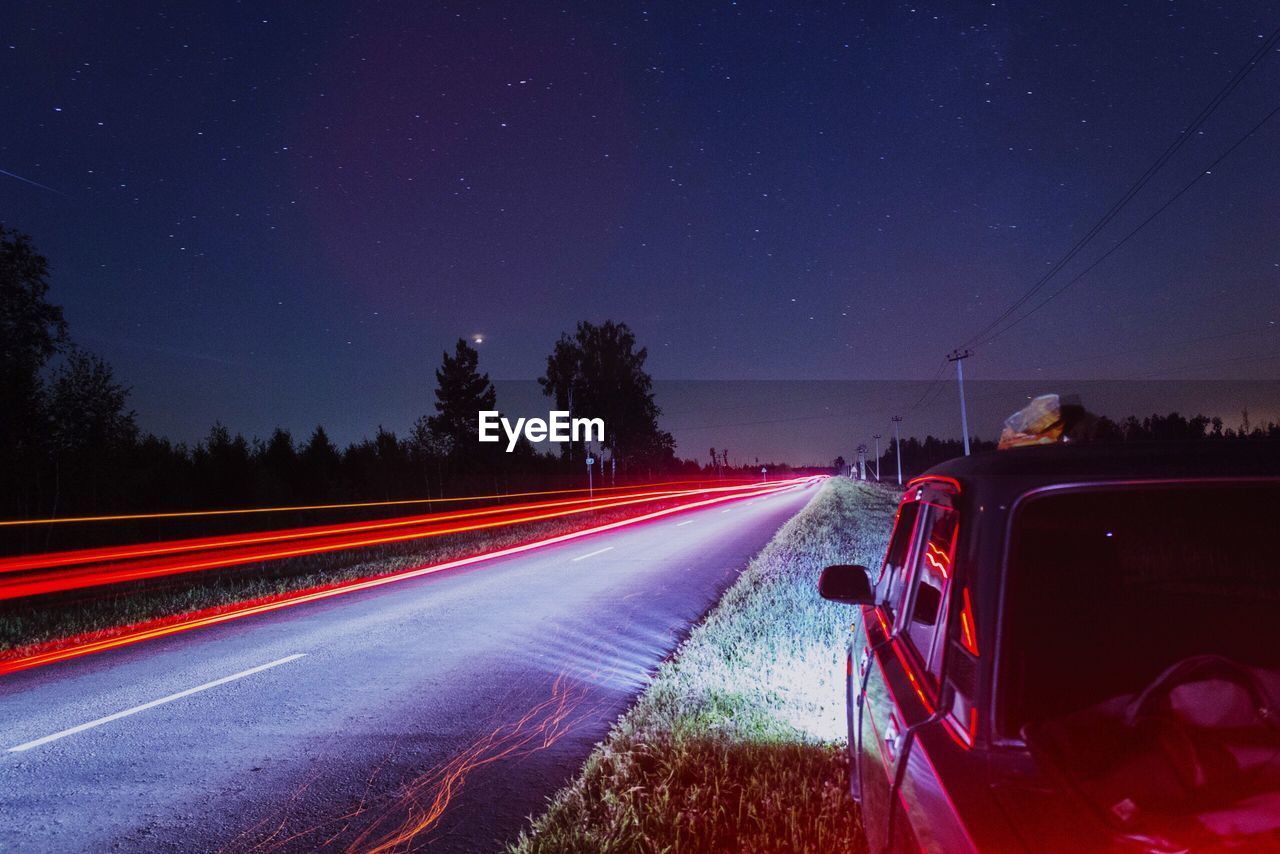 Light trails on road against sky at night