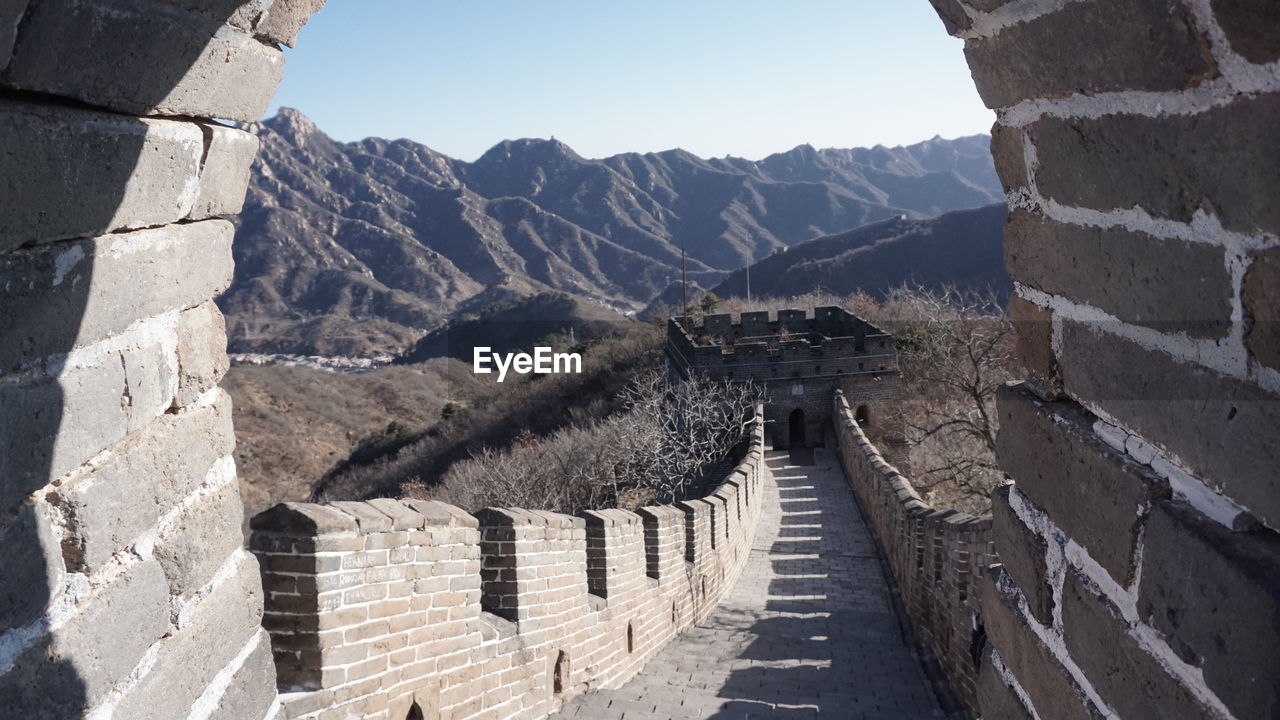 VIEW OF ARCHED WALL AGAINST MOUNTAIN