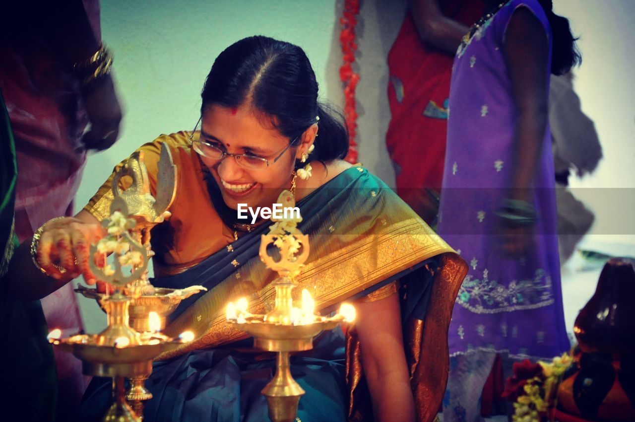 Smiling mid adult woman igniting diya at home