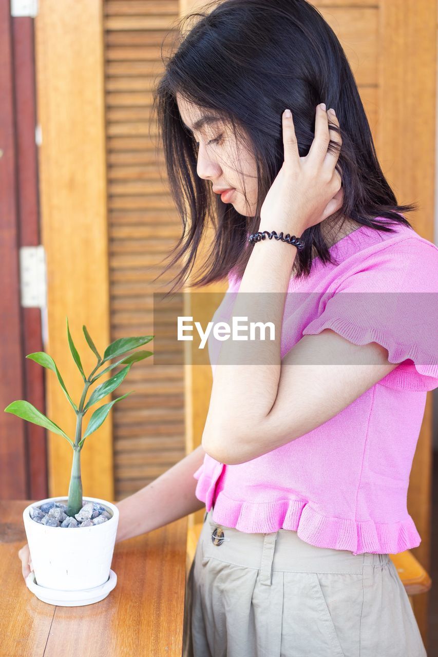 Midsection of woman holding pink potted plant on table. new normal life concept stay home .