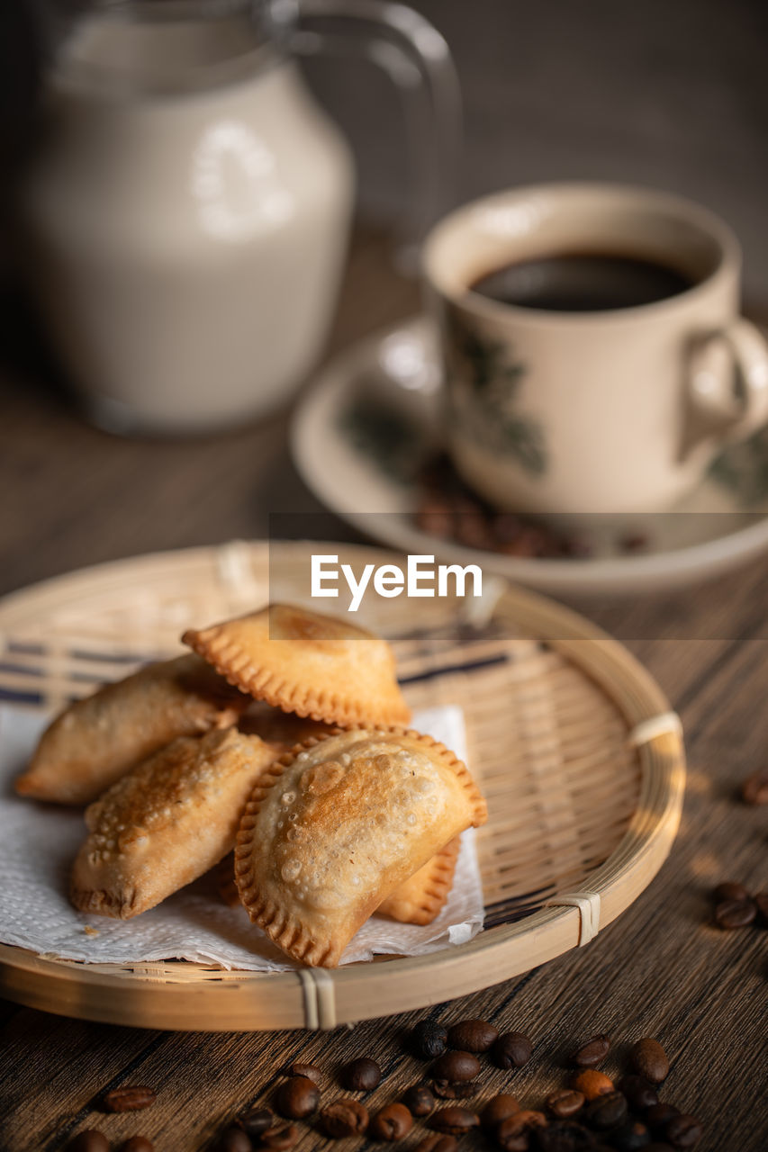 Fried curry puffs on a rattan plate with a cup of coffee. malaysian snacks. malaysian breakfast. 