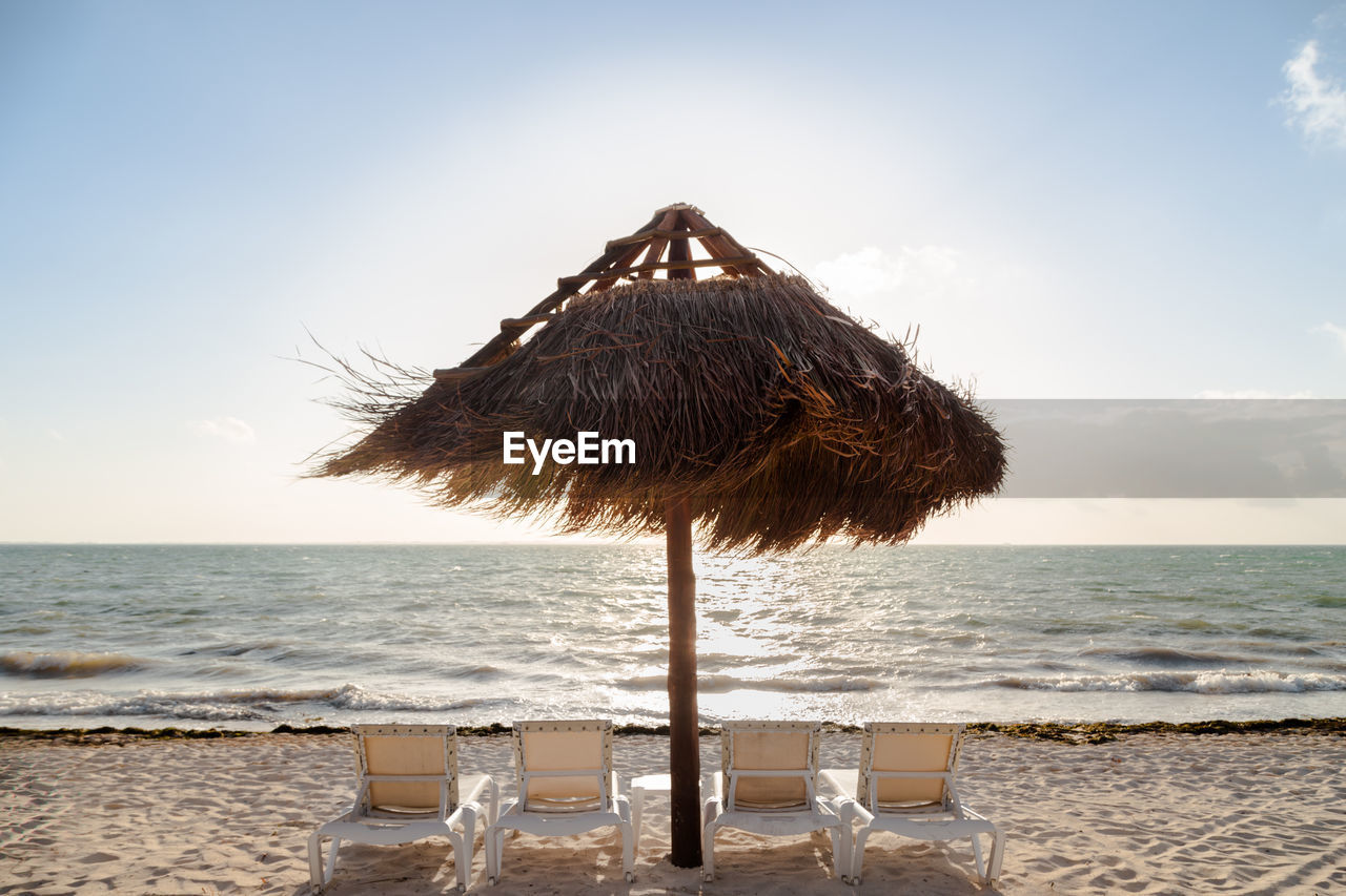 Thatched roof on beach against sky