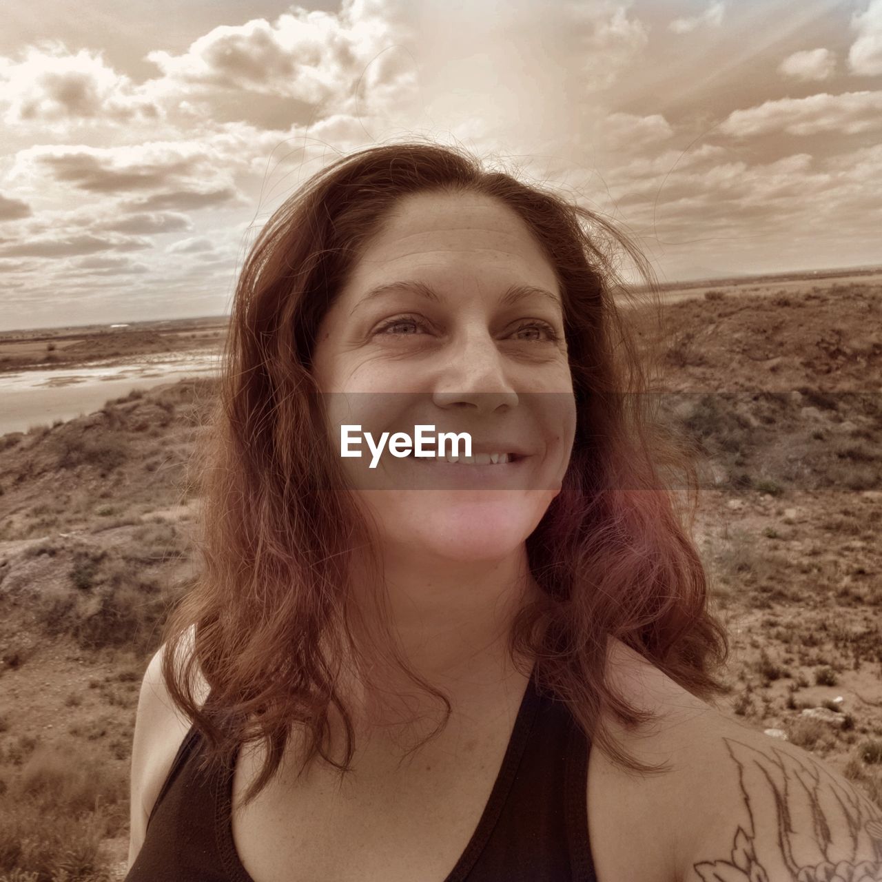 Smiling woman looking away at beach against sky