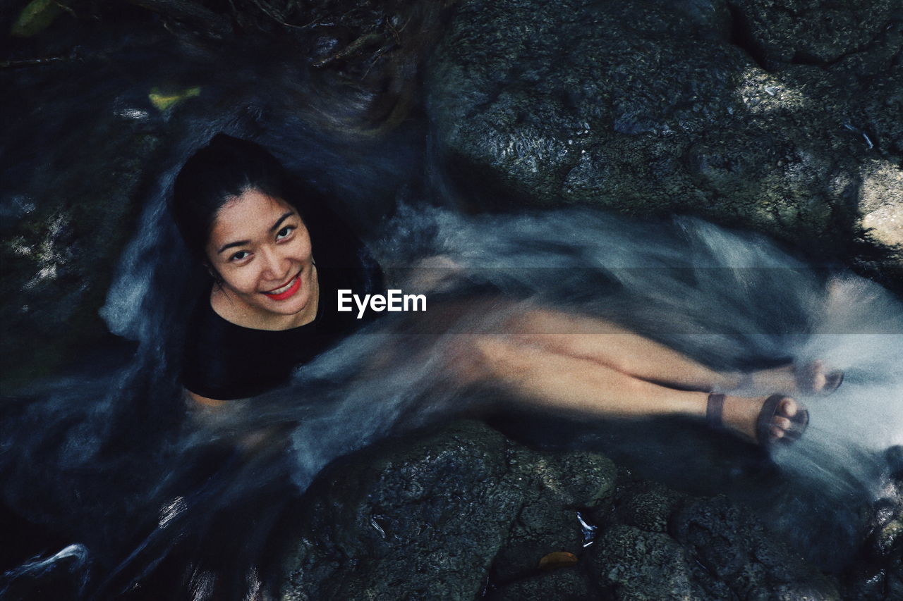 Portrait of smiling young woman on rock