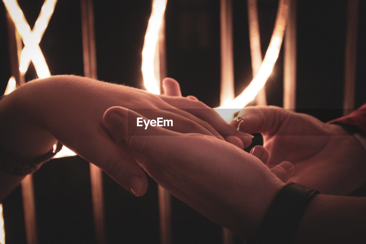 Close-up of couple holding hands at night