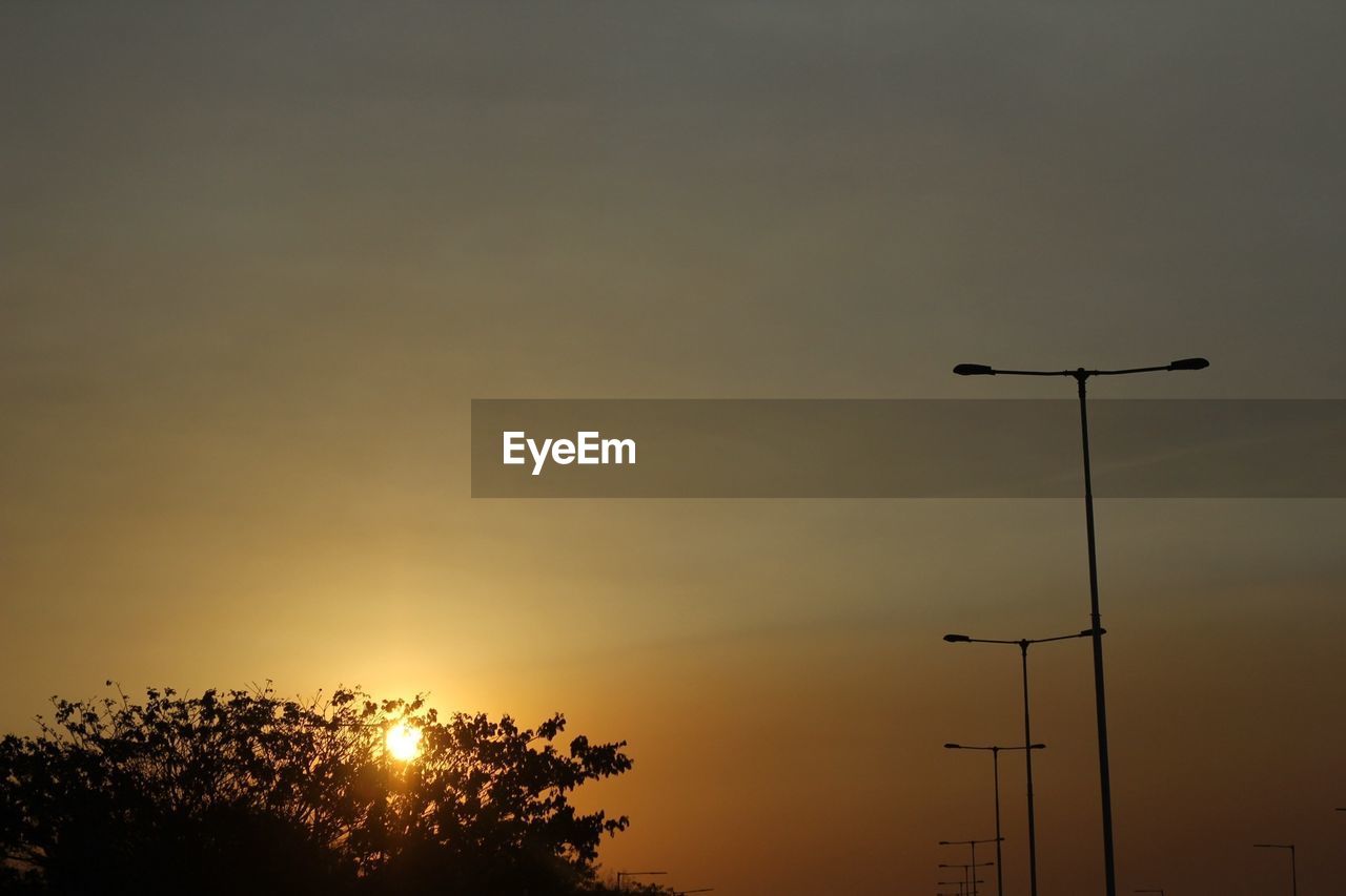 Low angle view of silhouette street lights against sky during sunset