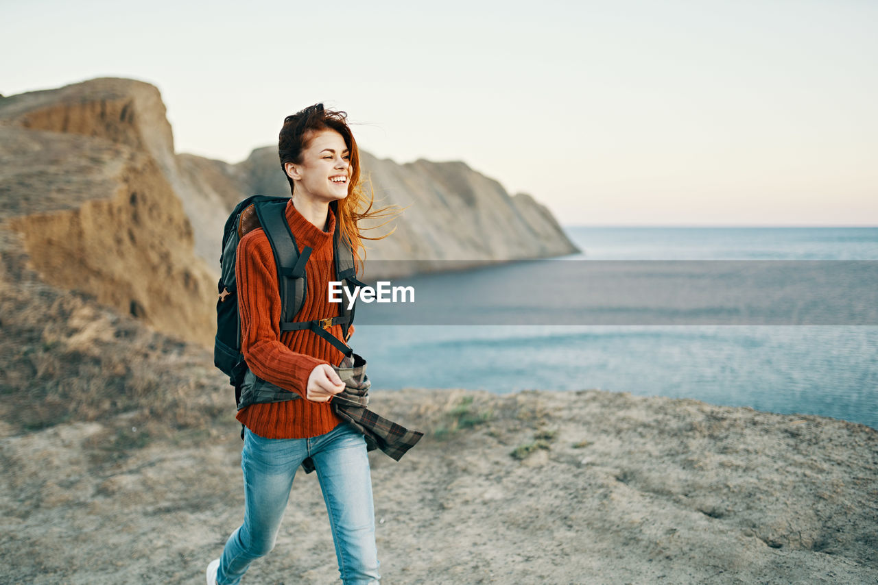 Full length of smiling young woman standing on beach