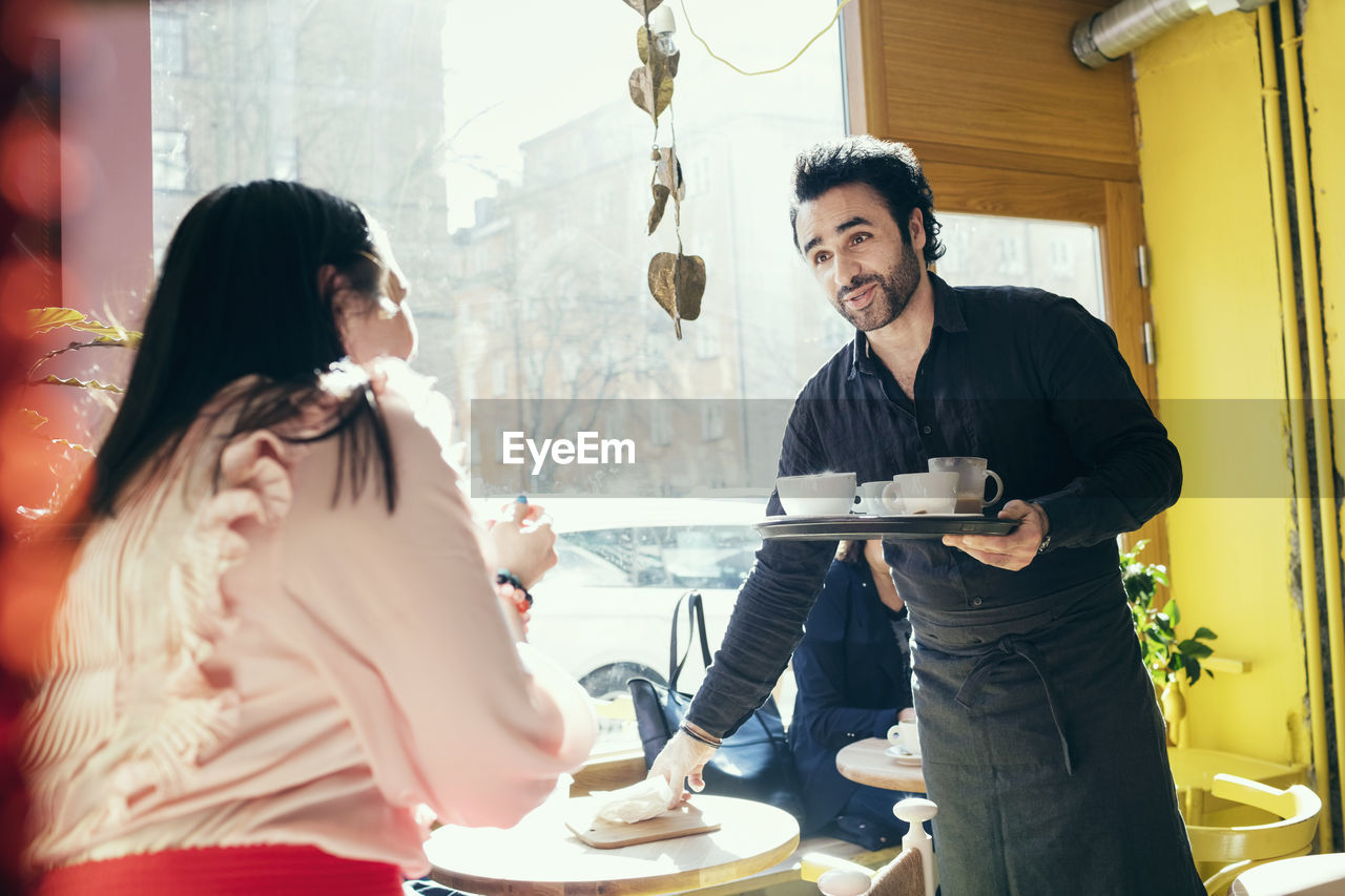 Barista serving to female customer at cafe