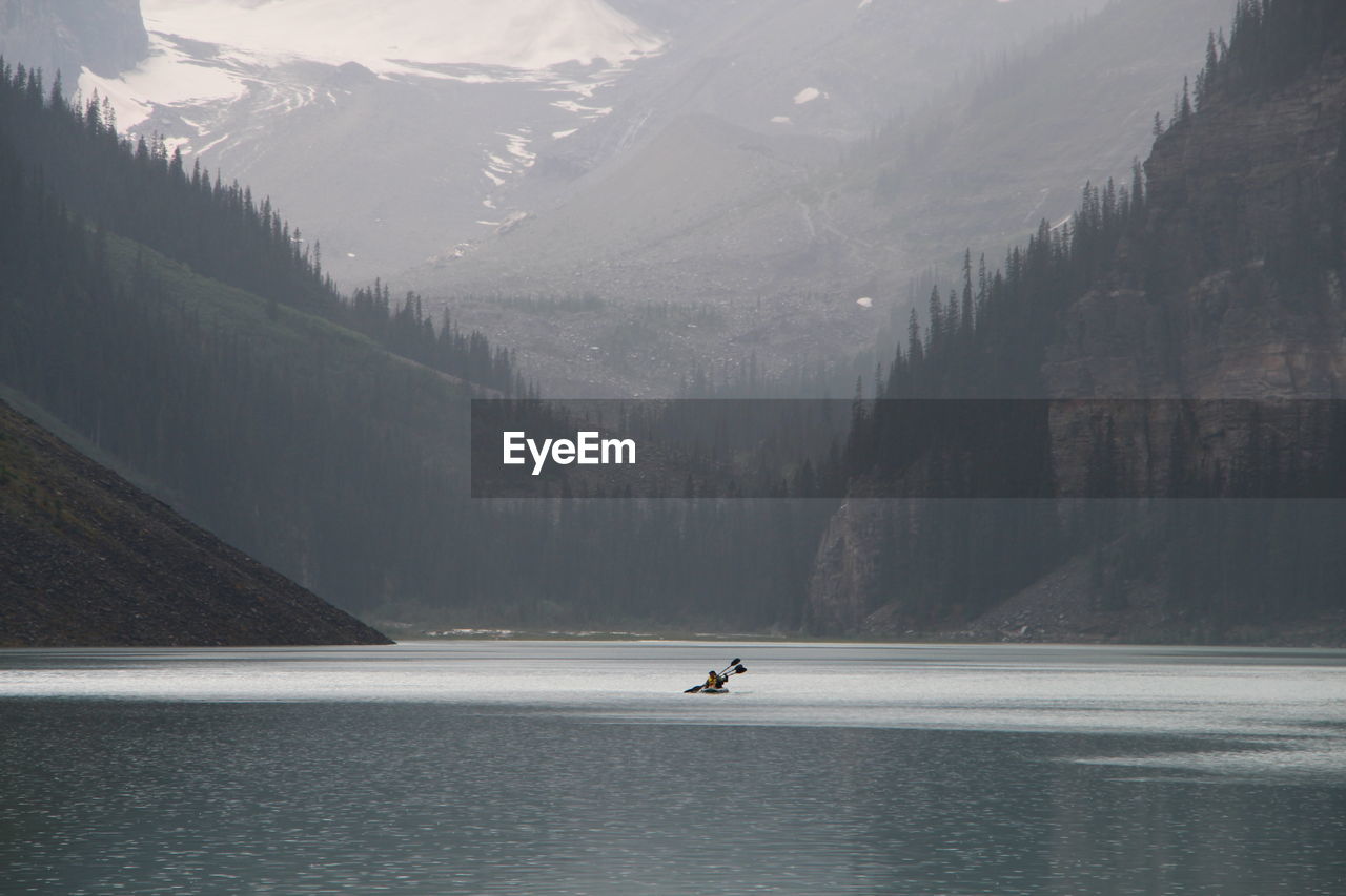 Kayaking across lake louise highlighting the vast water and dramatic landscape.