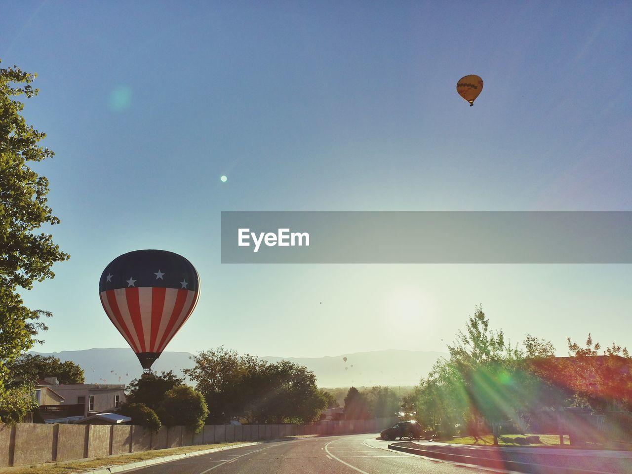 Low angle view of hot air balloon flying over road against clear sky