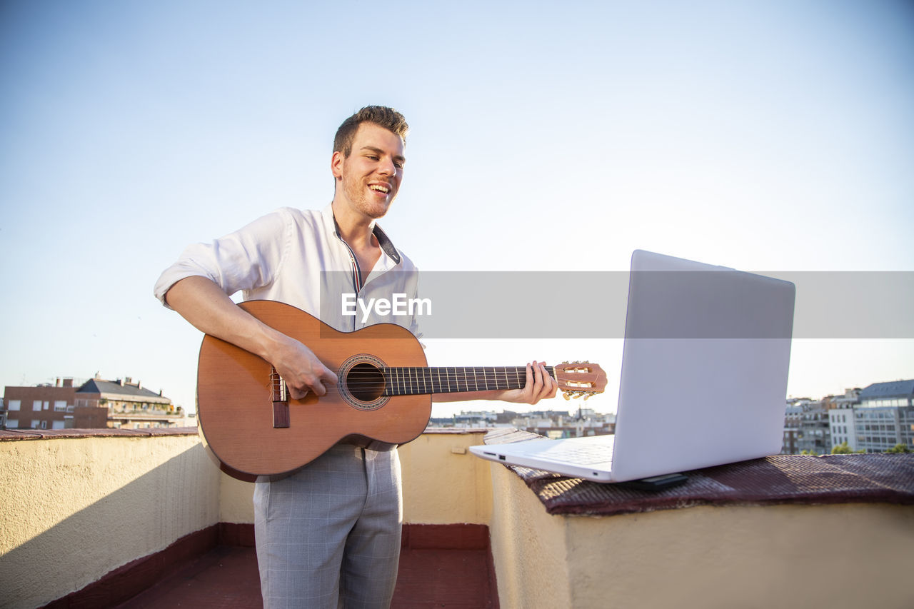 Handsome young singer performing for his fans on social media from the roof of his house during quarantine