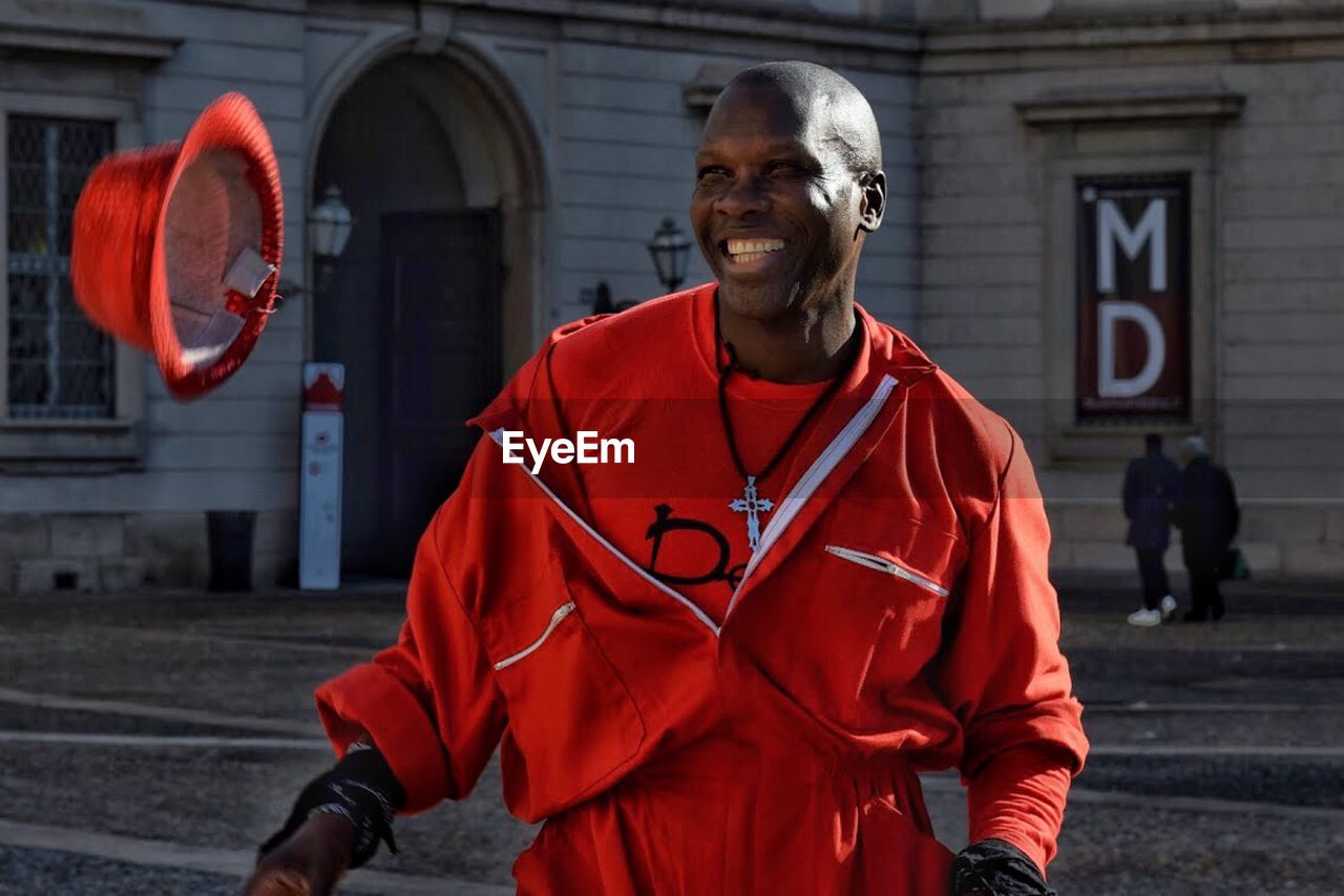 PORTRAIT OF MAN STANDING WITH RED UMBRELLA