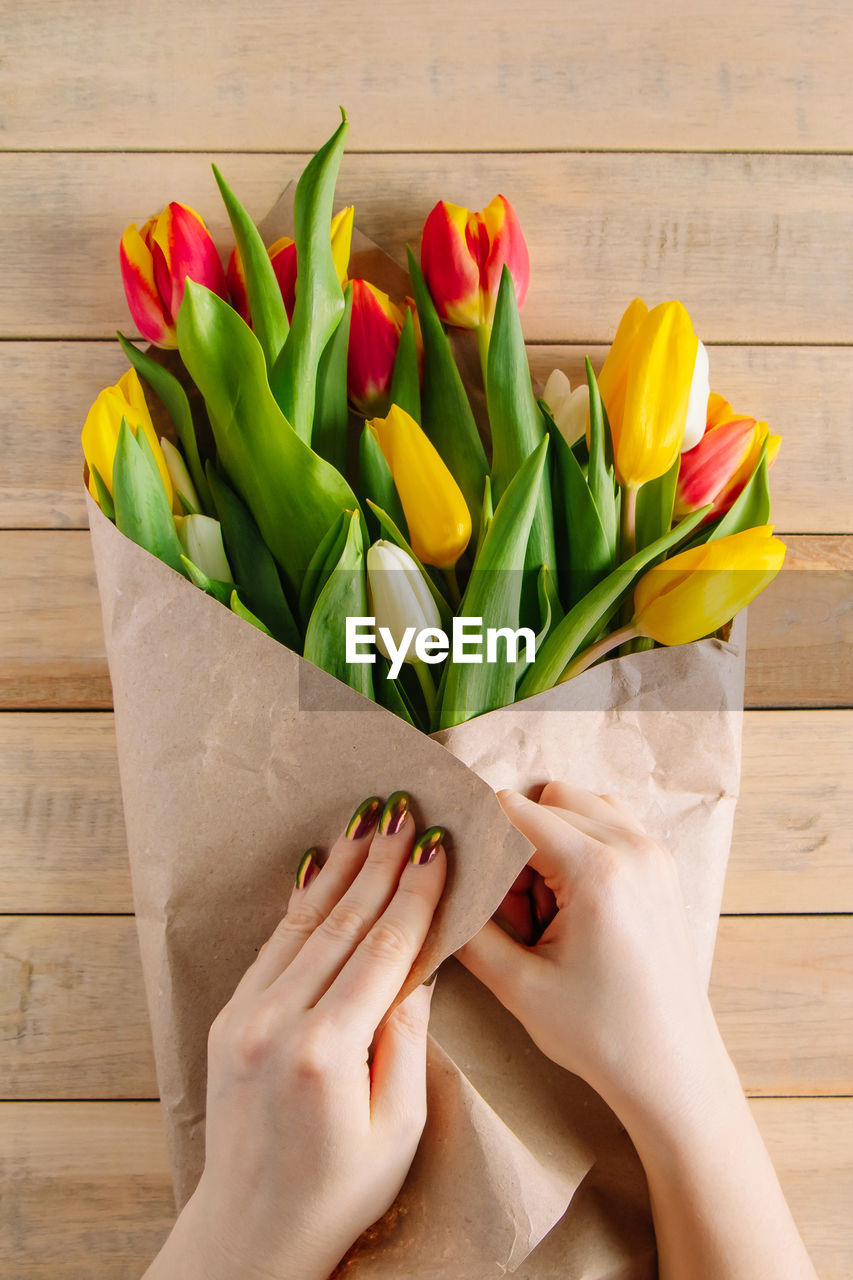 The process of wrapping bouquet of fresh tulips in eco-friendly craft paper. gift for spring holiday