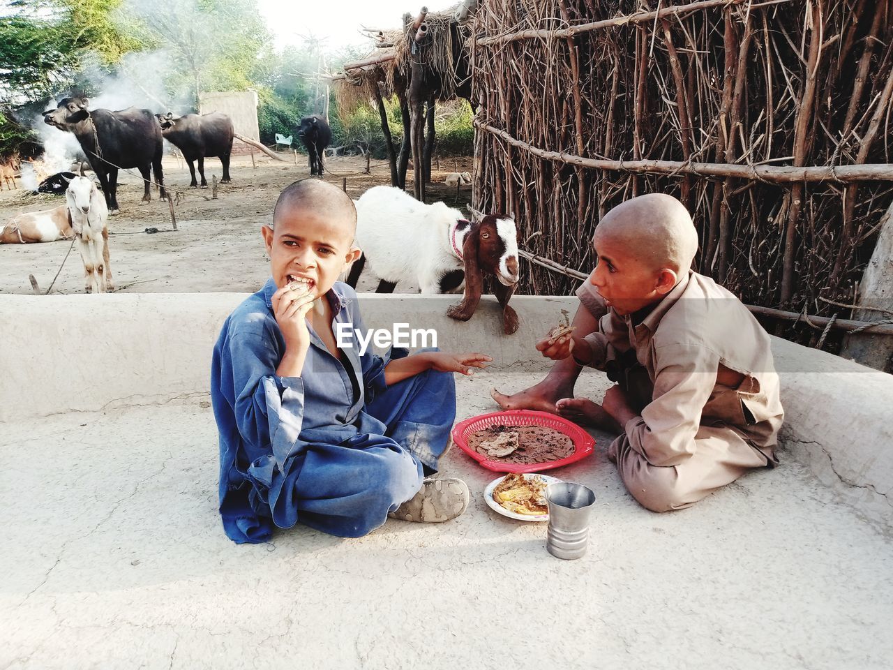 REAR VIEW OF FATHER AND DAUGHTER EATING WHILE SITTING ON FLOOR