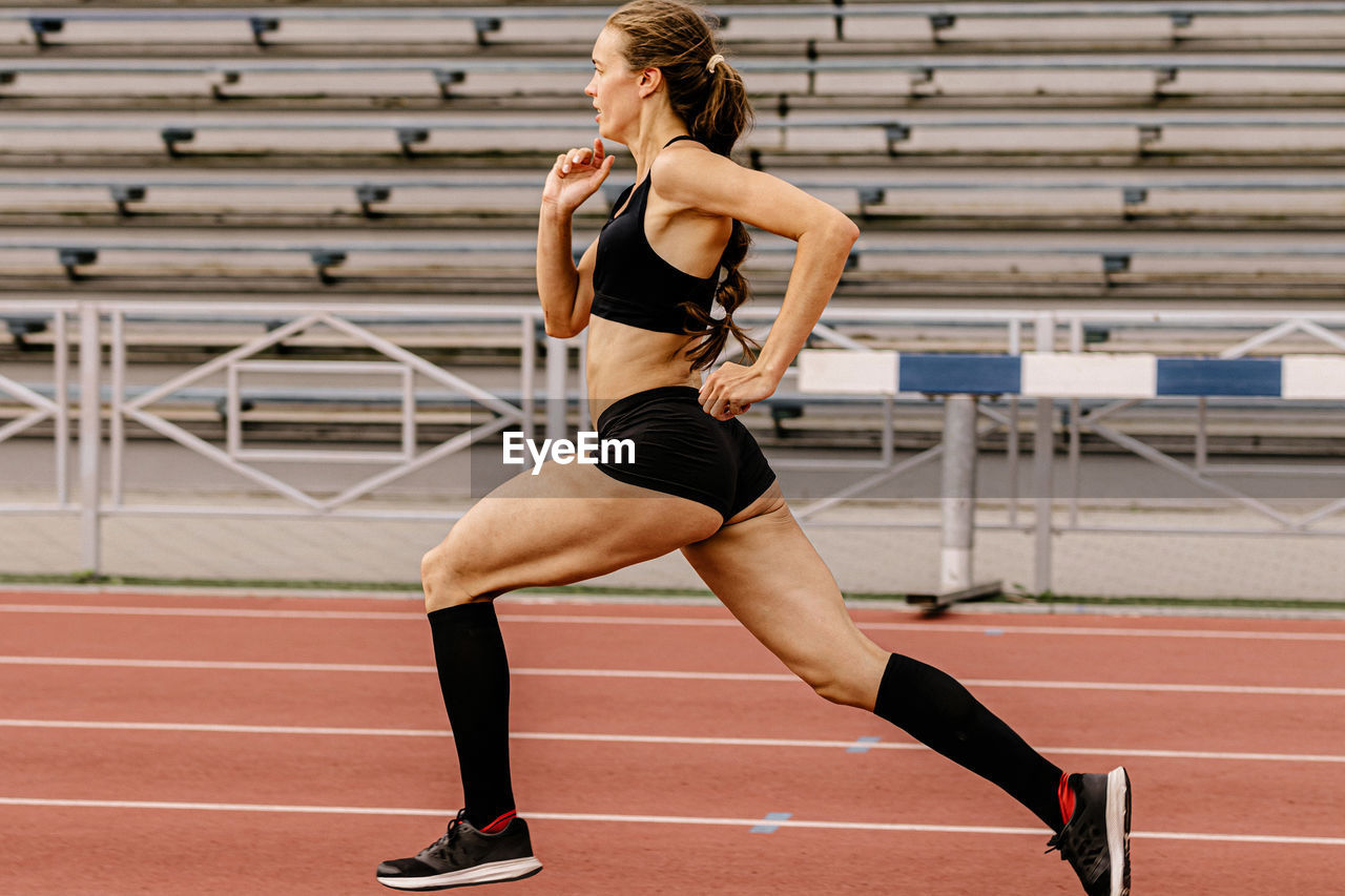 full length of young woman exercising on playing field