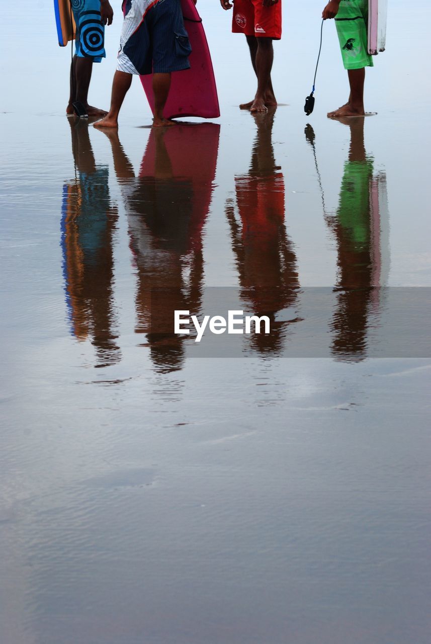 Low section of people standing on beach