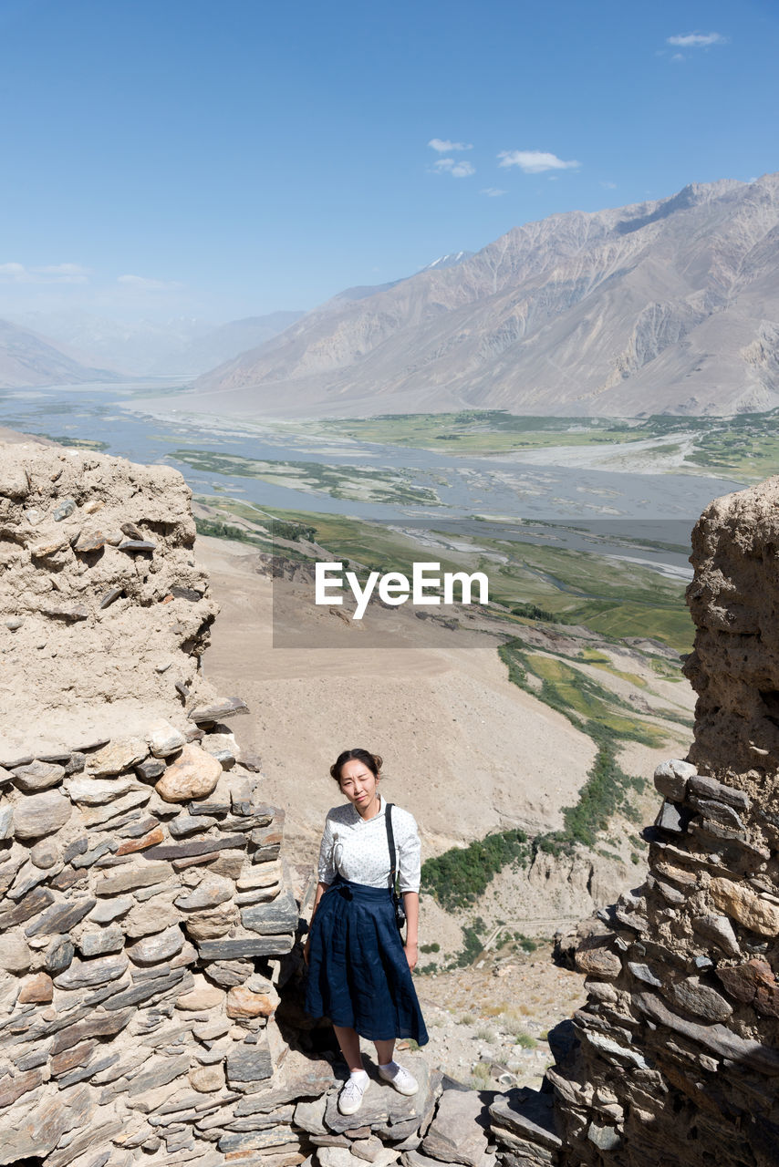 WOMAN STANDING ON MOUNTAIN AGAINST SKY