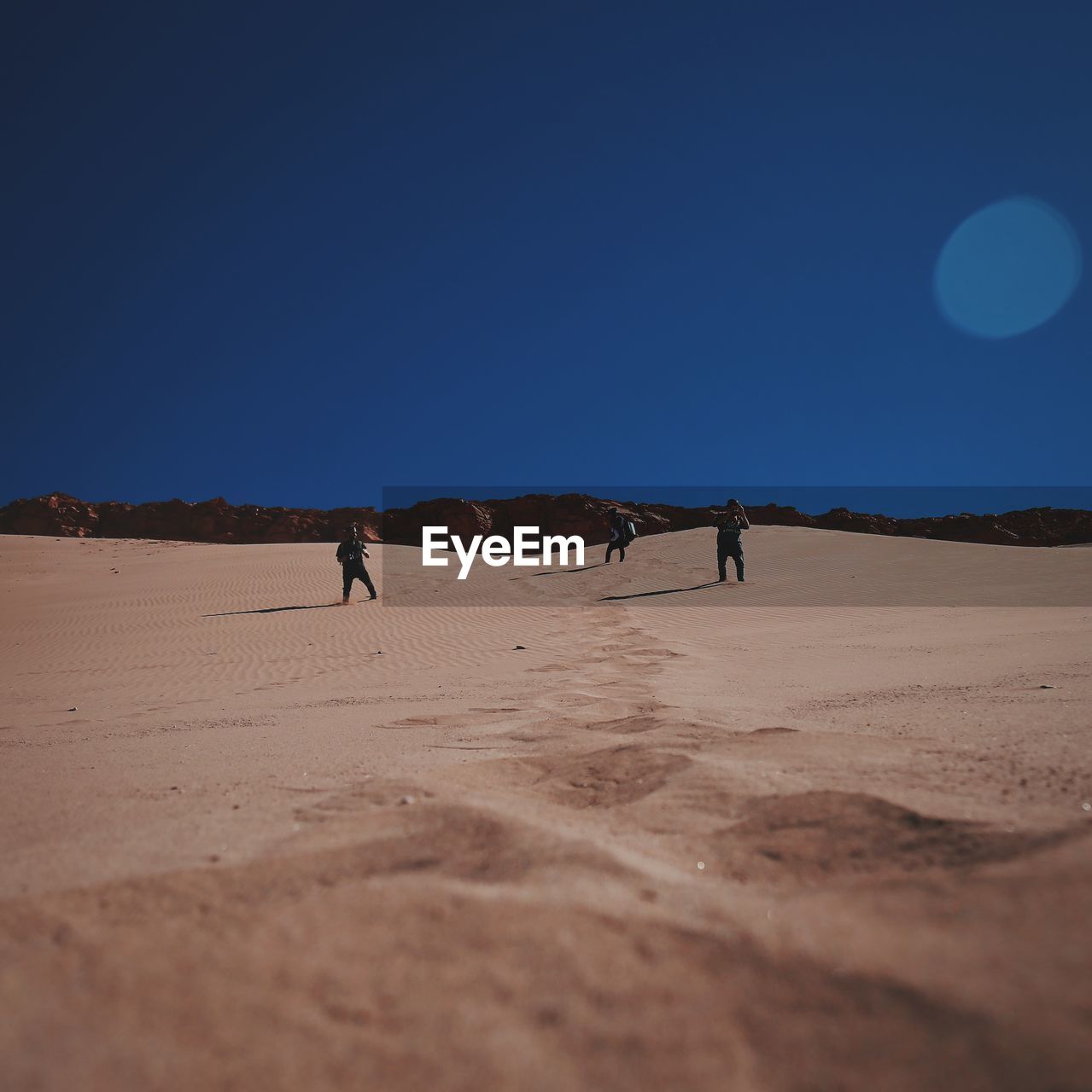 People standing in desert against clear sky