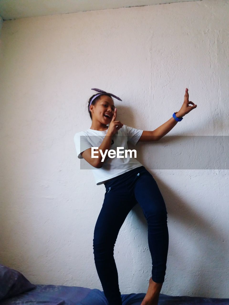 Teenage girl standing against wall