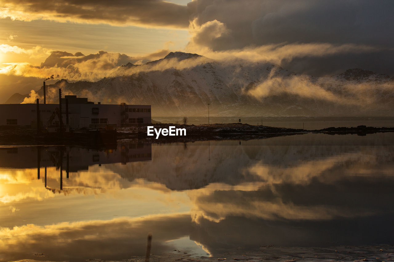 Scenic view of building by sea against sky during sunset